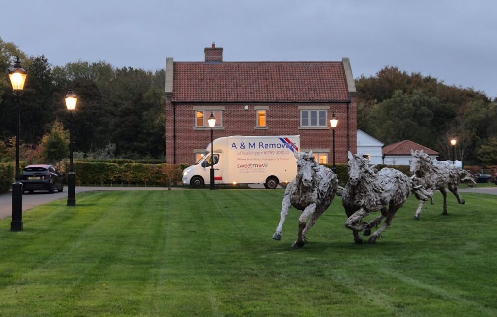 A&M Removals van outside a house with sculptures in the field